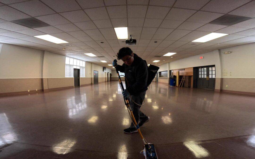 applying wax to a vct floor in a large even hall